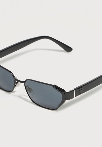 Μαύρα γωνιώδη γυαλιά ηλίου με σκούρους φακούς και λεπτά ορθογώνια σκελετάκια σε λευκό φόντο.