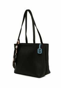 Fekete bőr tote táska texturált felülettel, két hosszú fogantyúval, egy kék címkével és egy díszes mintás sál kiegészítővel az egyik oldalon.