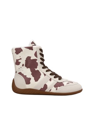 Zapatillas altas con un patrón de print de vaca en crema y marrón, con cordones marrones, acentos en blanco con tres rayas y una suela de goma texturizada.