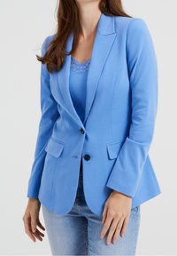 Jasnoniebieska marynarka wykonana z gładkiego materiału, z jednym guzikiem, kołnierzykiem typu lapel oraz dwiema przednimi kieszeniami i wąskimi rękawami.