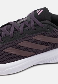 Purple mesh athletic shoe with black accents, featuring three brown stripes, lace-up design, and white outsole. Brand logo visible.