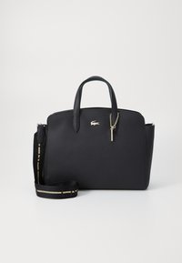 Sac à main en cuir noir texturé avec deux anses supérieures, bandoulière amovible, quincaillerie dorée et un petit accent en forme de charme.