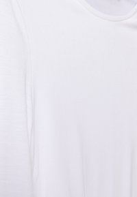 Weißes Baumwoll-T-Shirt mit einer glatten Textur, kurzen Ärmeln und einem Rundhalsausschnitt. Einfach und minimalistisch im Aussehen.