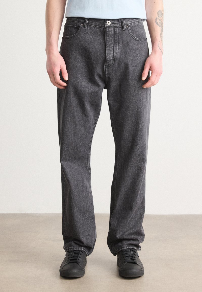 Mørkegrå denim jeans med lige ben, knaplukning, forlommer og let indsnørede manchetter. Sammen med sorte sneakers.