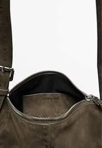 Borsa in suede verde oliva con texture liscia e zip color argento. L'interno presenta un rivestimento nero e l'etichetta "Massimo Dutti" ben visibile.
