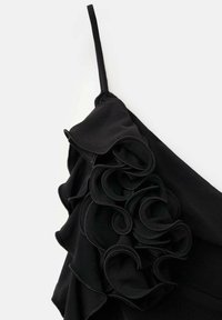 Black dress featuring a ruffled design made of soft fabric. It has a thin strap and intricate pleating along the ruffle edges.