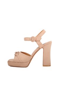 Sandali platform in suede beige con tacco largo, punta aperta e cinturino alla caviglia rotondo con fibbia. Presentano un dettaglio annodato sulla parte anteriore.