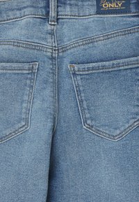 Svetlomodré džíny s klasickým strihom, s dvoma zadnými vreckami a viditeľnými švami. Tkanina vykazuje jemnú štruktúru.