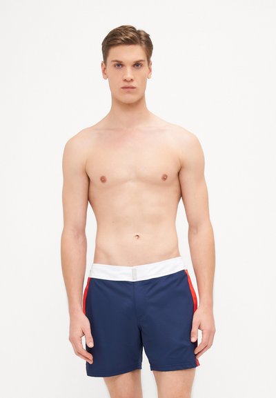 Shorts de bain navy avec une taille blanche et des accents rouges sur les côtés. Fabriqués en matériau léger, offrant un ajustement confortable et sans motifs visibles.