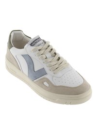 Zapatilla de cuero blanca con un acento de gamuza gris y un logo de tela azul. Presenta cordones redondos, puntera perforada y suela de goma beige.