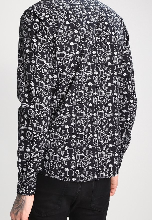 Camisa de manga larga de tela negra con un patrón blanco de equipos de audio y accesorios. Cuello abotonado, corte recto y puños.