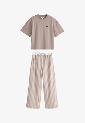 Short-sleeve beige top with "self." logo and light beige wide-leg pants with thin vertical stripes and a branded elastic waistband.
