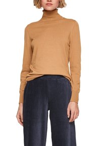 Světle hnědý rolák vyrobený z měkké látky, s dlouhými rukávy a volným střihem, doplněný námořnickými ribbovanými kordovými kalhotami.