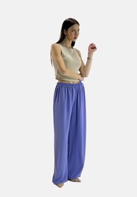 Lichtbeige mouwloze top gecombineerd met losse, helder lavendelkleurige wijde broek met elastische tailleband. Soepele textuur, minimalistisch ontwerp.