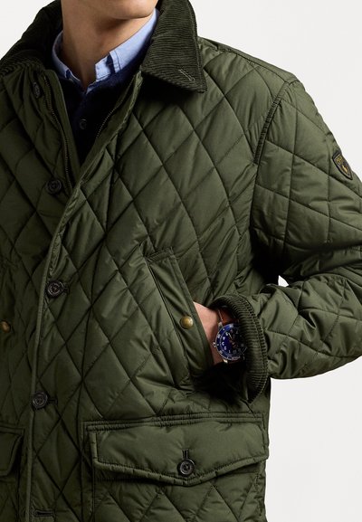Quilted green jacket with a corduroy collar, large buttons, and flap pockets; features a textured fabric and a stylish wristwatch.
