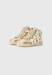 Gold metallic high-top sneakers with beige lace-up design, featuring a white side decorated with large gold polka dots and a zip closure.