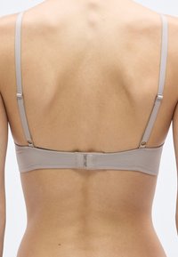 Μπεζ σουτιέν με ρυθμιζόμενες τιράντες, λεία υφασμάτωση και κούμπωμα με γαντζάκι. Διαθέτει απλό σχεδιασμό, χωρίς διακοσμητικά ή σχέδια.
