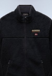 Black fleece jacket with a zip-up front, high collar, two side pockets, and a logo patch featuring gold and red accents. Soft, textured surface.