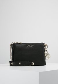 Czarna skórzana torebka typu crossbody z teksturowaną powierzchnią, srebrnymi okuciami, łańcuszkowym paskiem i detalami z logo. Posiada zamek błyskawiczny oraz odpinany pasek.