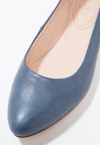 Modré kožené baleríny s kulatou špičkou a světlým béžovým vnitřním stélkou, na které je vyražený vzor z kůže.