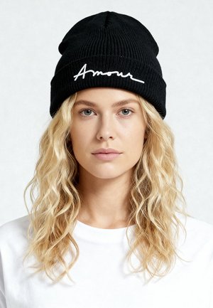 Cappello a cuffia nero lavorato a maglia con la parola "Amour" ricamata in corsivo bianco. Texture a coste con una vestibilità morbida e flessibile.