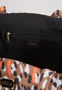 Sac à main imprimé léopard marron et multicolore avec un intérieur noir, doté d'une poche zippée et d'une étiquette logo dorée. Texture douce.