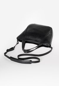 Zwarte leren tas met een slank, afgerond ontwerp aan de bovenkant, verstelbare schouderriem en subtiele stiksels. Glad oppervlak en minimalistische esthetiek.