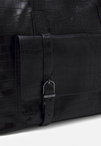 Sac à main en cuir noir texturé avec motif crocodile, doté d'un rabat avant sécurisé par une fine sangle avec une boucle argentée gravée "Esprit".