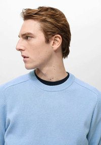 Pulover tricotat de culoare bleu deschis, cu guler rotund, având un guler interior de culoare bleu închis contrastant și o textură subtilă. Design simplu, ajustat.