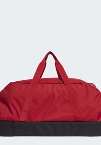 Crvena platnena torba s dva gornja ručka, zatvaranjem na patentni zatvarač i crnim donjim panelom za izdržljivost. Glatka tekstura s minimalnim detaljima.
