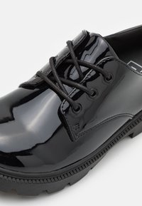 Schwarze Lacklederschuhe mit glänzender Oberfläche, runder Zehenform und strukturiertem Gummisohle. Mit schwarzen Schnürsenkeln und minimalistischem Design.