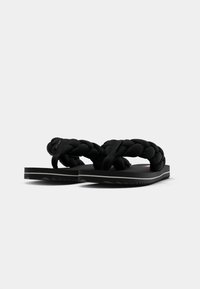 Svarta flip-flops med flätade tygremmar, platt gummisula, texturerad undersida för grepp och minimalistisk design utan extra utsmyckningar.