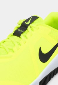 Φωτεινό κίτρινο αθλητικό παπούτσι με διχτυωτό ύφασμα, μαύρες λεπτομέρειες και ετικέτα "JUST DO IT" στη γλώσσα. Διαθέτει υφασμάτινη σόλα για καλύτερη πρόσφυση.