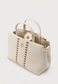 Δερμάτινη τσάντα χρώματος κρέμα με δύο χερούλια, κλείσιμο με φερμουάρ και αντίθετο διακριτικό σχέδιο σε κόκκινο και ναυτικό μπλε. Χρυσόχρωμες λεπτομέρειες.