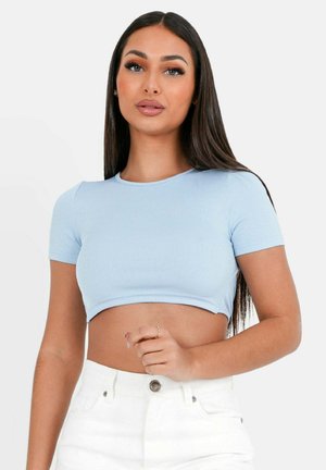 Crop top côtelé bleu clair à manches courtes, associé à un short blanc taille haute. Texture lisse et design ajusté.