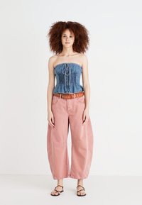 Blå denim strapless topp med samlet detalj, kombinert med lyserøde vide bukser og et brunt belte. Svart sandaler med stropper fullfører antrekket.