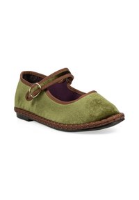 Zapato de ante verde con puntera redondeada, correa marrón asegurada con una hebilla de metal y detalle trenzado en la suela marrón. El interior presenta un forro púrpura.