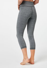 Grå capri leggings med hög midja, tillverkade av texturiserat, stretchigt tyg. Har en slät yta och svarta sömnadsdetaljer vid fållen.