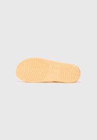 Orange rubber sole with a textured pattern, featuring curved and straight grooves for grip. Smooth finish with logo imprint.