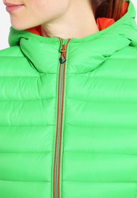 Zielona pikowana kurtka z kapturem, z poziomym przeszyciem, zamkiem błyskawicznym z przodu ozdobionym pomarańczowymi akcentami oraz gładką, błyszczącą fakturą.