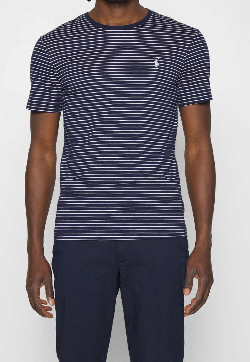 Námořnické a bíle pruhované tričko s kulatým výstřihem a krátkými rukávy. Obsahuje malé vyšívané logo na hrudi.