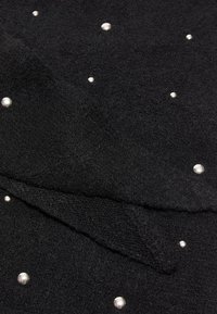 Tessuto nero con una consistenza morbida, caratterizzato da perline simili all'argento sparse sulla superficie, con pieghe sovrapposte visibili.