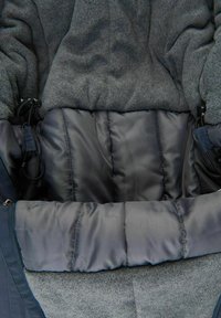 Grå isolerad jacka med interiör av mjuk fleece och satinliknande foder, med puffkant och justerbar dragsko för ökad komfort.