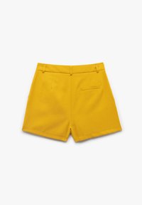 Pantaloni corti gialli con una texture liscia, design strutturato, due tasche frontali, una tasca posteriore e lunghezza a metà coscia.