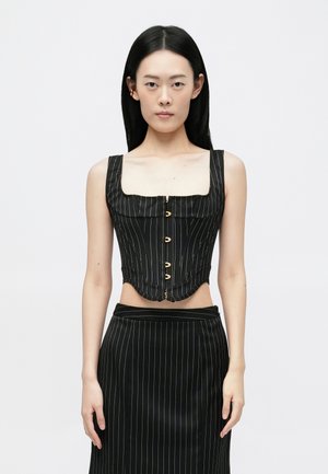 Melnas svītrainas korsetes tops ar kvadrātveida kakla izgriezumu, pogu aizdari un izliekto apakšējo malu; apvienots ar atbilstošām svītrainām svārkiem.