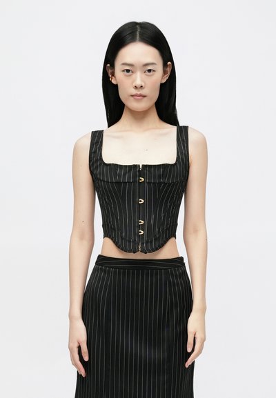 Top corsetto a righe nere con scollatura quadrata, chiusura con bottoni e orlo curvo; abbinato a una gonna a righe coordinate.