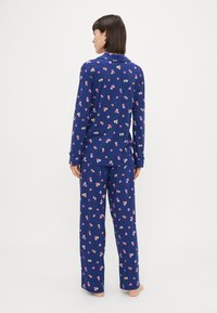 Conjunto de pijama azul-marinho com padrões florais em rosa, amarelo e branco, com mangas longas e calças soltas, feito de tecido macio.