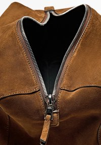 Brown suede bag with a silver zipper, featuring a wide opening and a smooth inner lining. Textured surface and notable zipper detail.