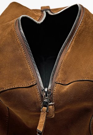 Brown suede bag with a silver zipper, featuring a wide opening and a smooth inner lining. Textured surface and notable zipper detail.