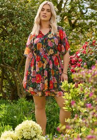 Musta kukallinen mekko lyhyillä hihoilla, vyötärölle yhteensidetty, jossa on vaaleanpunaisia, punaisia ja keltaisia kukkia; läpikuultava pinta, virtaava muotoilu.